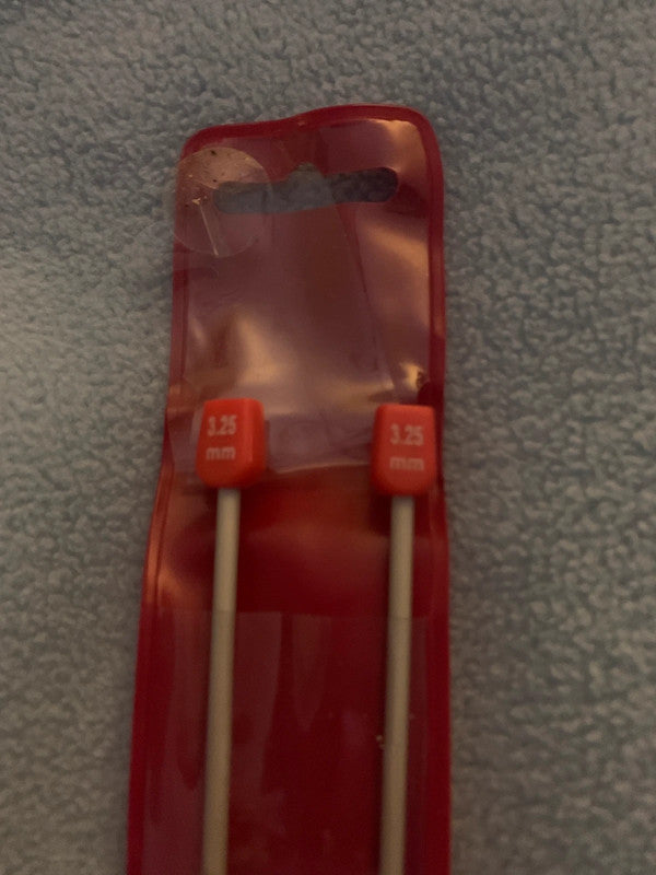 These are a pair of 3.25 mm knitting needles in their original red plastic packaging.
